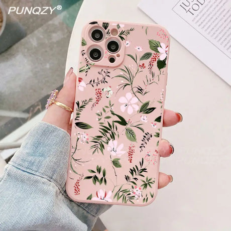 A woman holding a pink phone case with floral print