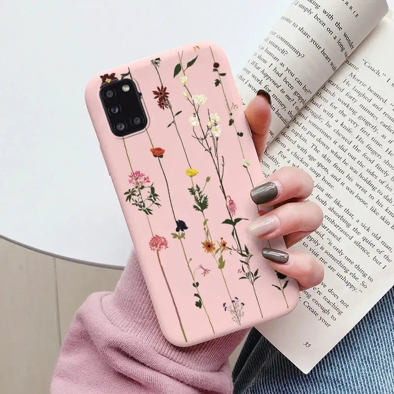 a woman holding a pink phone case with flowers on it