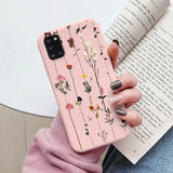 A woman holding a pink phone case with flowers on it