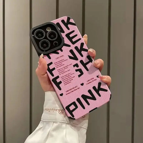 A woman holding a pink phone case with the words pink