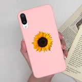 a woman holding a pink phone case with a sunflower on it
