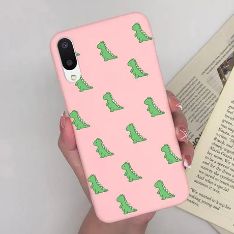 a woman holding a pink phone case with green alligators on it