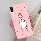a woman holding a pink phone case with a heart on it