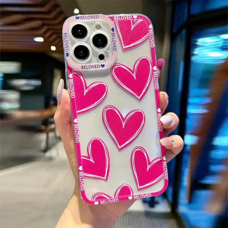 a woman holding a pink phone case with hearts on it