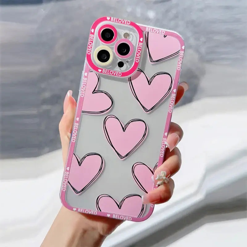 a woman holding a pink phone case with hearts
