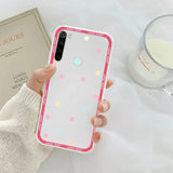 a woman holding a pink and white polka dot phone case
