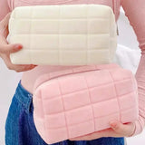 a woman holding a pink and white quilted purse