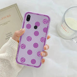 a woman holding a purple phone case with hearts on it