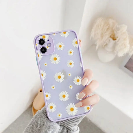 A woman holding a purple phone case with white daisies on it