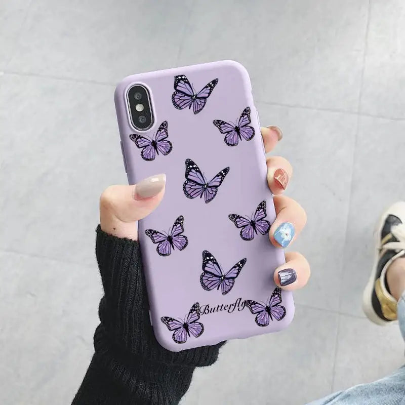 A woman holding a purple phone case with butterflies on it