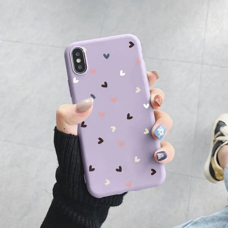 A woman holding a purple phone case with hearts on it