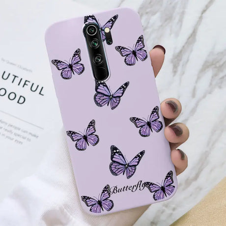 A woman holding a purple phone case with butterflies on it