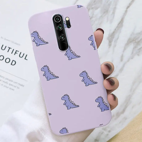 A woman holding a purple phone case with a pattern of blue cats on it