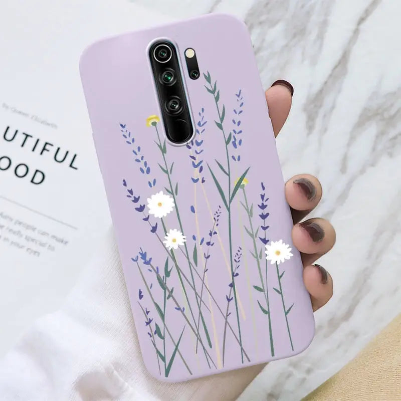 a woman holding a purple phone case with flowers on it