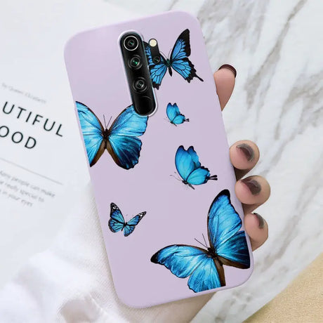 A woman holding a purple phone case with blue butterflies on it