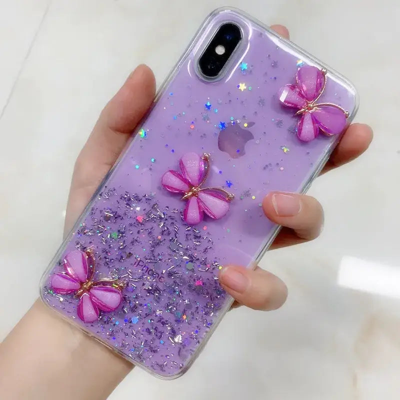 A woman holding a purple phone case with glitter butterflies