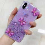 a woman holding a purple phone case with glitter butterflies