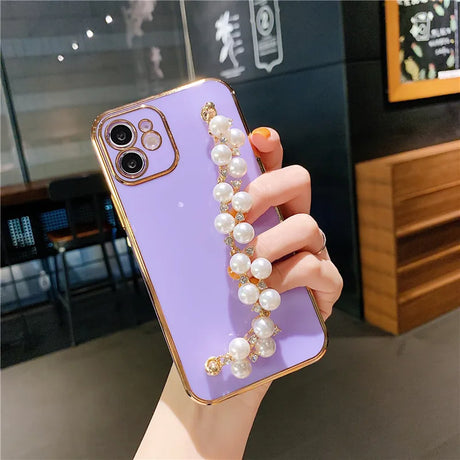 a woman holding a purple phone case with pearls