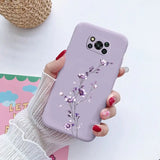 a woman holding a purple phone case with flowers on it