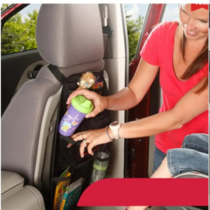 a woman is putting a bottle of water in the back seat of a car