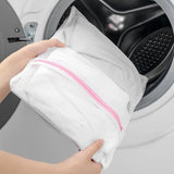 a woman is putting a laundry bag into the washing machine