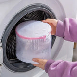 a woman is putting a mesh bag into a washing machine