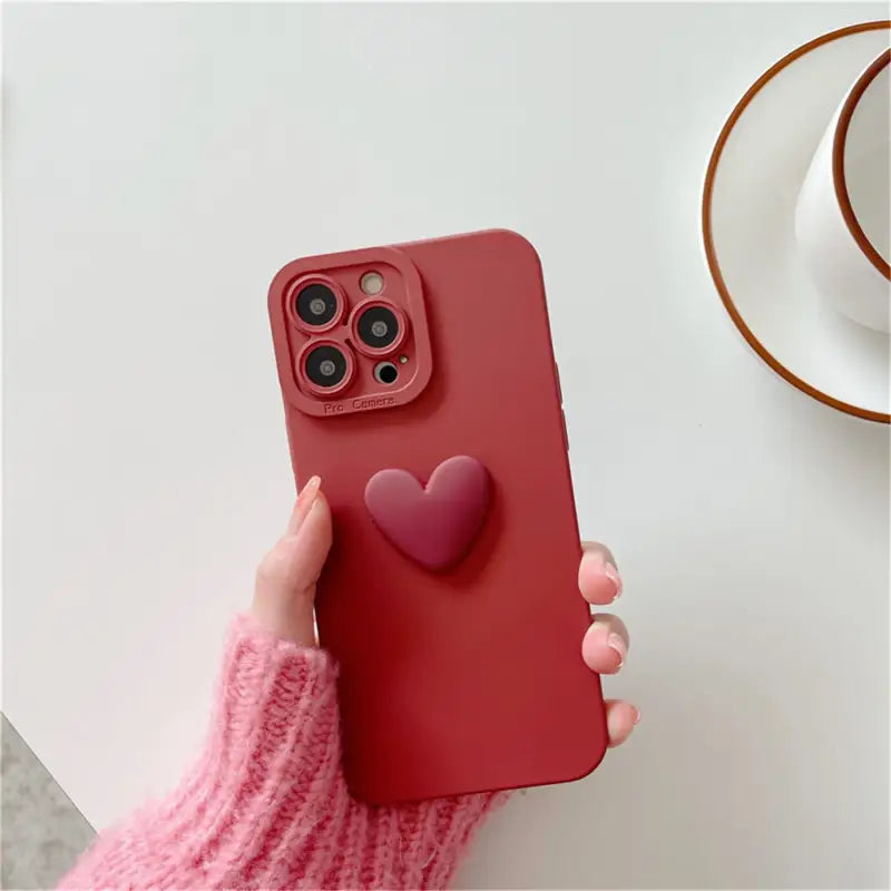 a woman holding a red iphone case with a heart