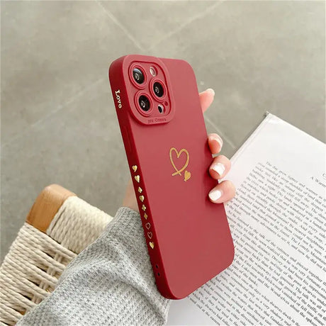 A woman holding a red phone case with gold heart