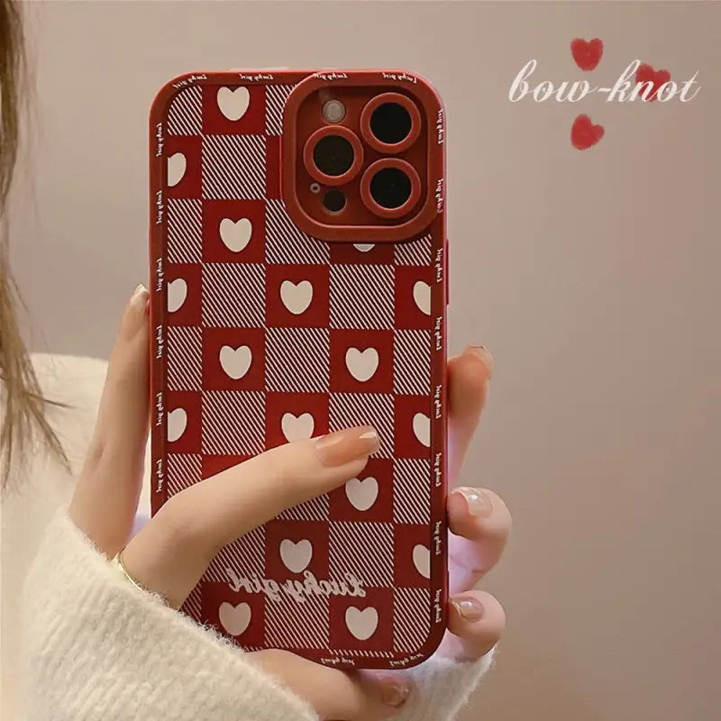 a woman holding a red and white iphone case