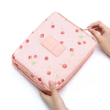 a woman’s hand holding a pink bag with a strawberry print