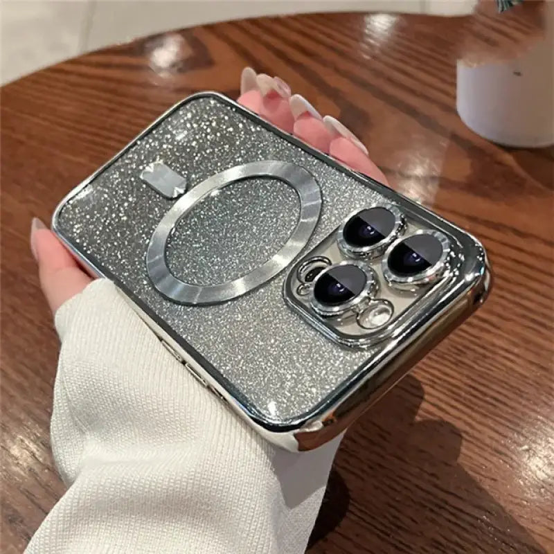 a woman holding a silver glitter phone case