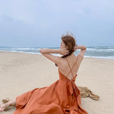 a woman in an orange dress sitting on the beach
