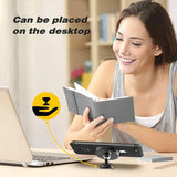 a woman sitting at a desk with a laptop and a book