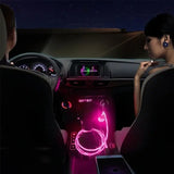 a woman sitting in the back seat of a car with a pink light on it