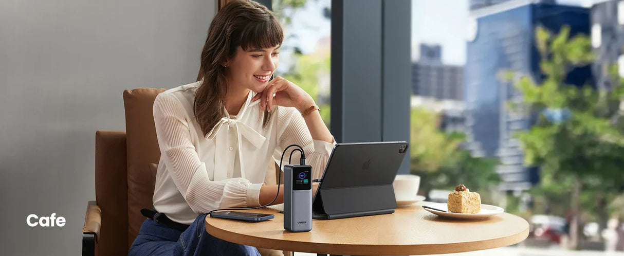 Woman sitting at a table with a tablet and drink.