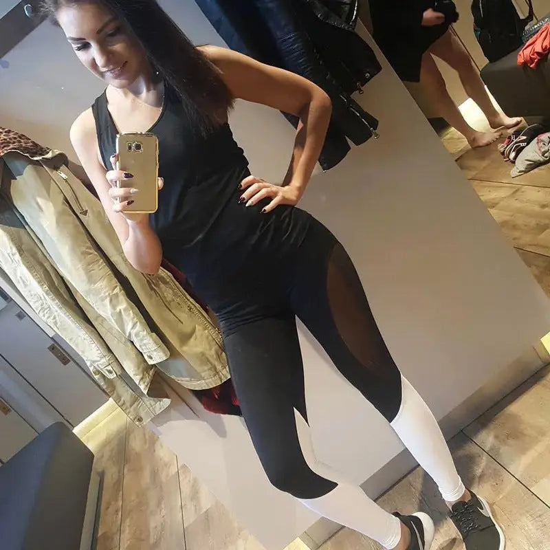a woman in black top and leggings standing in front of mirror