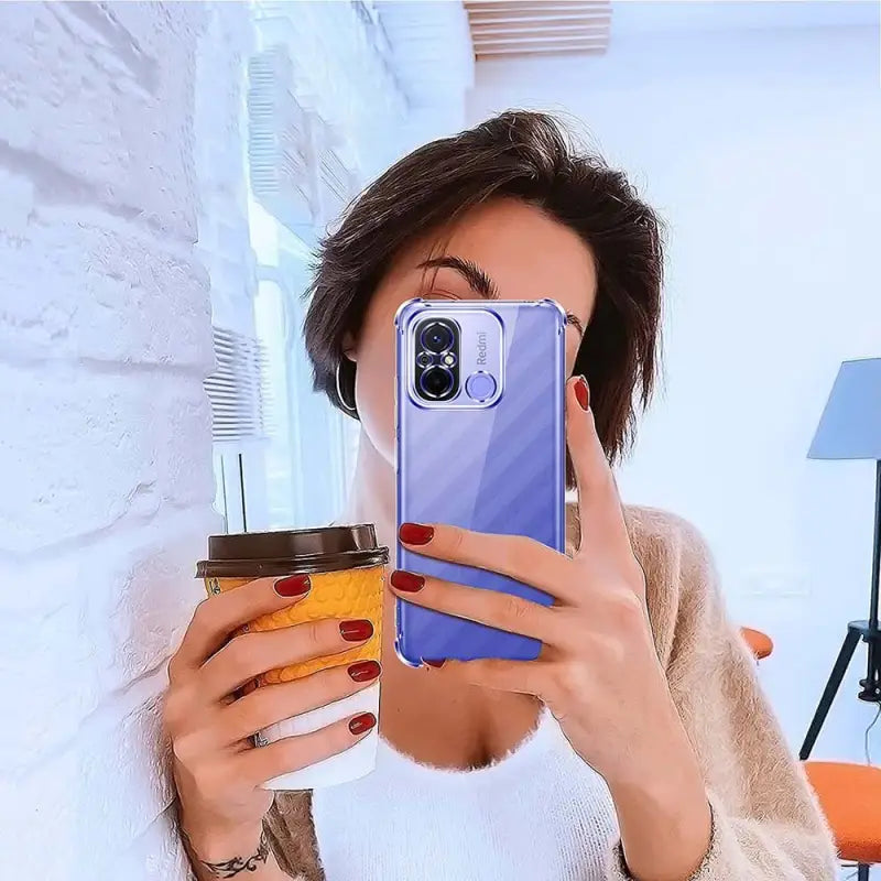woman taking a selfie with her phone while holding a coffee