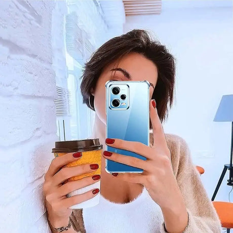 woman taking a selfie with her phone while holding a coffee