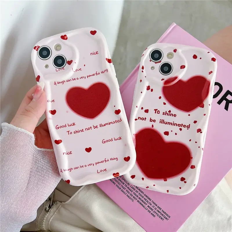 A woman holding two cell cases with hearts on them