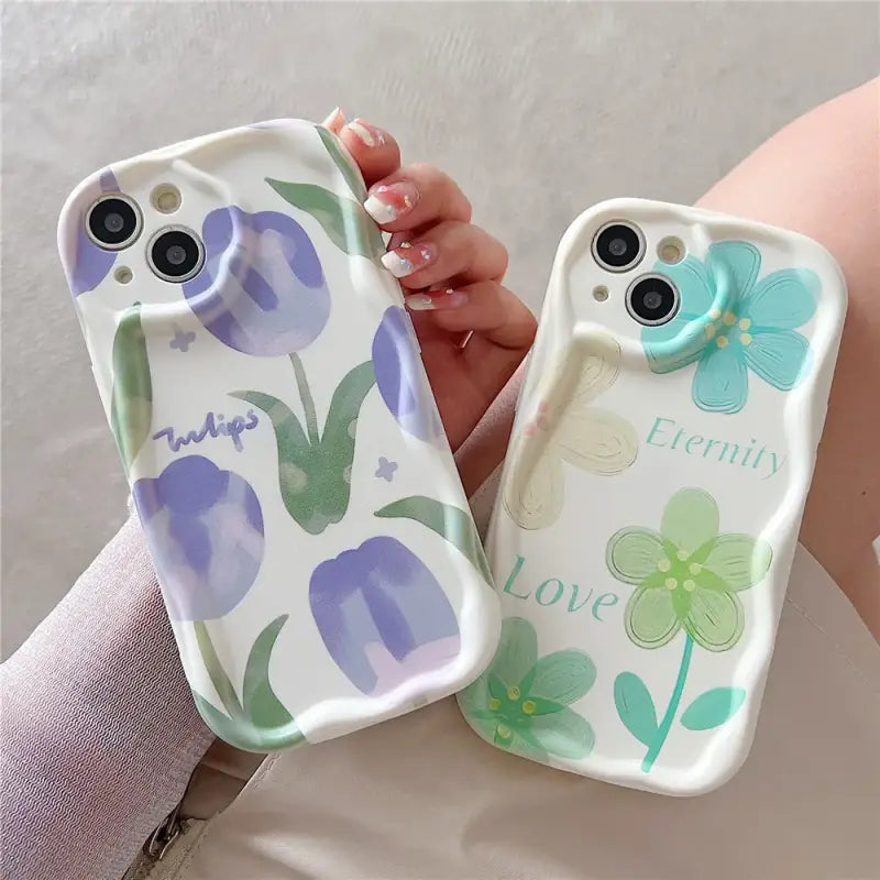 a woman holding two cell cases with flowers on them