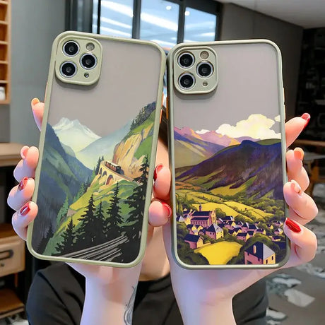 A woman holding two iphone cases with a mountain scene