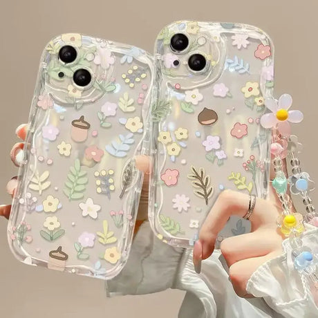 a woman holding two iphone cases with flowers on them