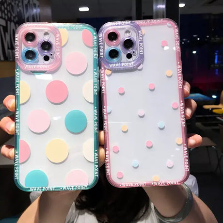 a woman holding two iphone cases with colorful circles on them