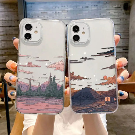 A woman holding two iphone cases with a landscape design