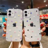 A woman holding up two iphone cases with flowers and hearts