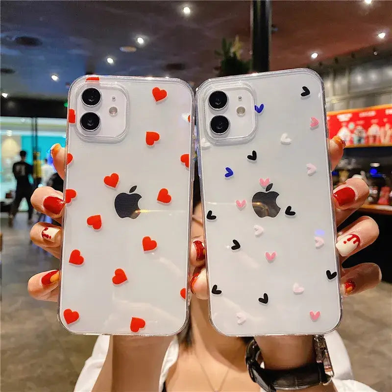 A woman holding up two iphone cases with hearts on them