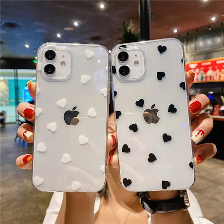 A woman holding up two iphone cases with hearts on them