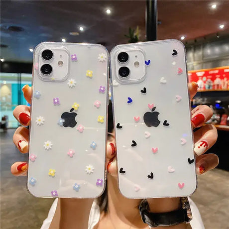 A woman holding up two iphone cases with flowers and hearts