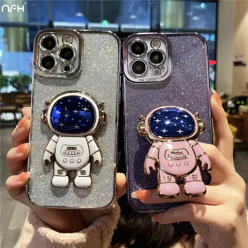 A woman holding up two phone cases with a spaceman and astronaut