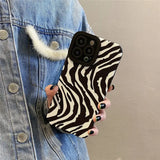 a woman wearing a denim jacket and denim jacket holding a phone case with zebra print